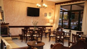 Un hall d’hôtel doté de plusieurs espaces salon, d’un téléviseur à écran plat fixé au mur et de grandes fenêtres avec des rideaux.