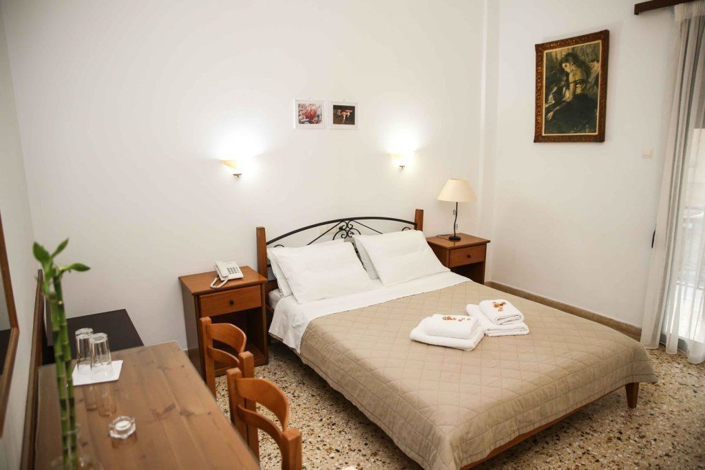 A hotel room with a bed, bedside table, lamp, and a desk with chairs.