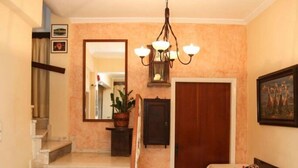 Un hall d’hôtel avec un escalier en marbre, un lustre, un comptoir d’accueil et un miroir au mur.