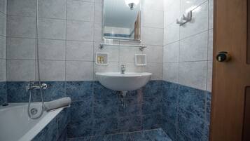 Une salle de bain avec un lavabo blanc, un miroir au-dessus et une douche avec une serviette.