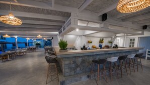 Un área de bar moderna con mostrador de piedra, taburetes y lámparas de mimbre colgantes.