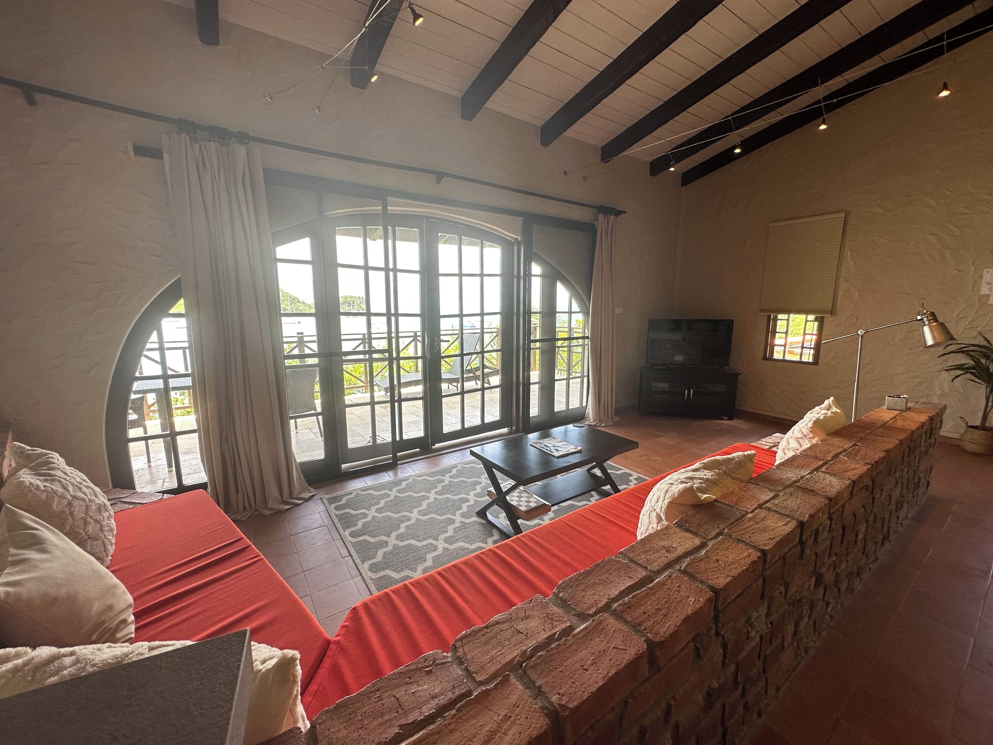 A spacious living area with a large sliding glass door leading to an outdoor patio, a television, and a brick accent wall.