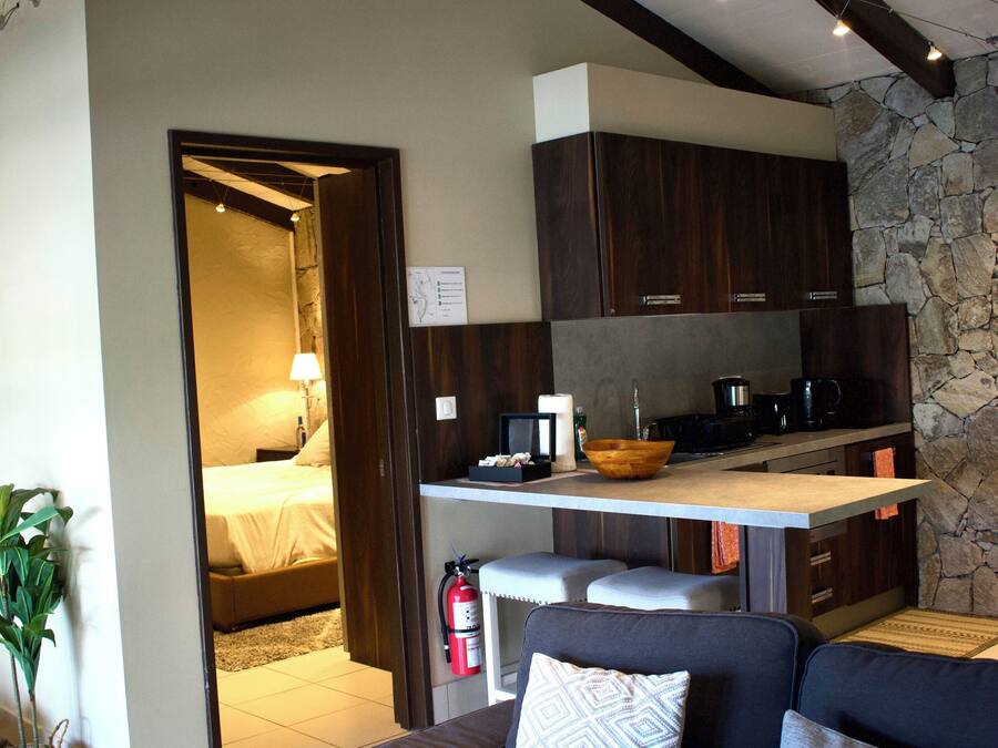 Una sala moderna con un sofá y una cocina visible a través de un vano abierto.
