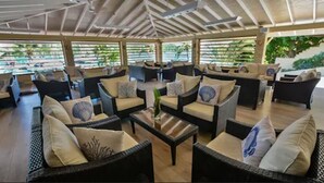 Un espacio de estar al aire libre cubierto con mobiliario de mimbre y una mesa de centro.