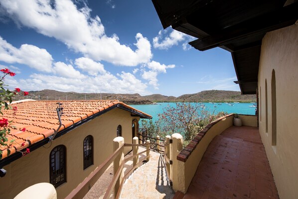 Ein Balkon mit Blick auf ein türkisblaues Meer und ferne Hügel.