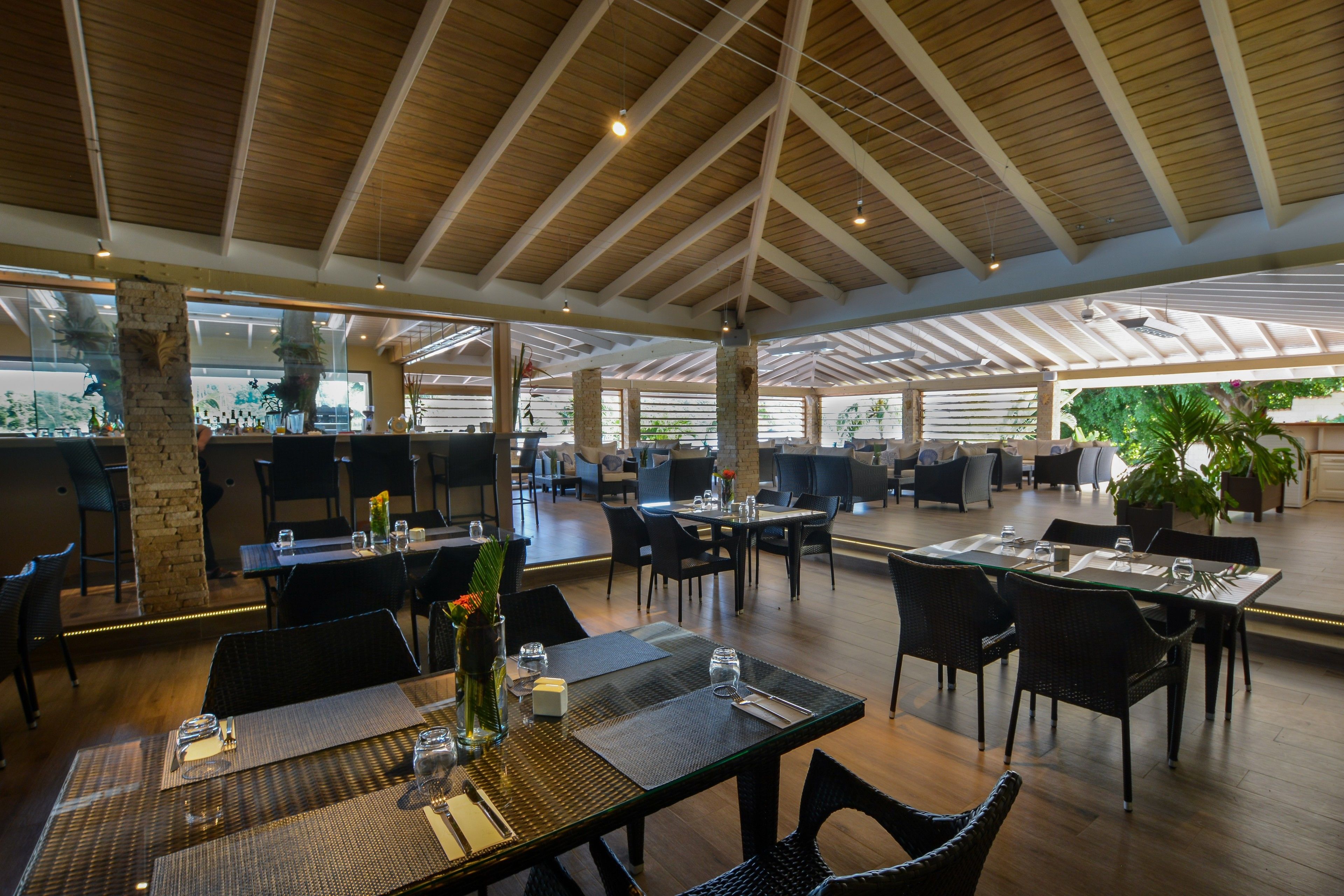 A spacious restaurant with high ceilings and natural light. Tables are set with placemats and cutlery.