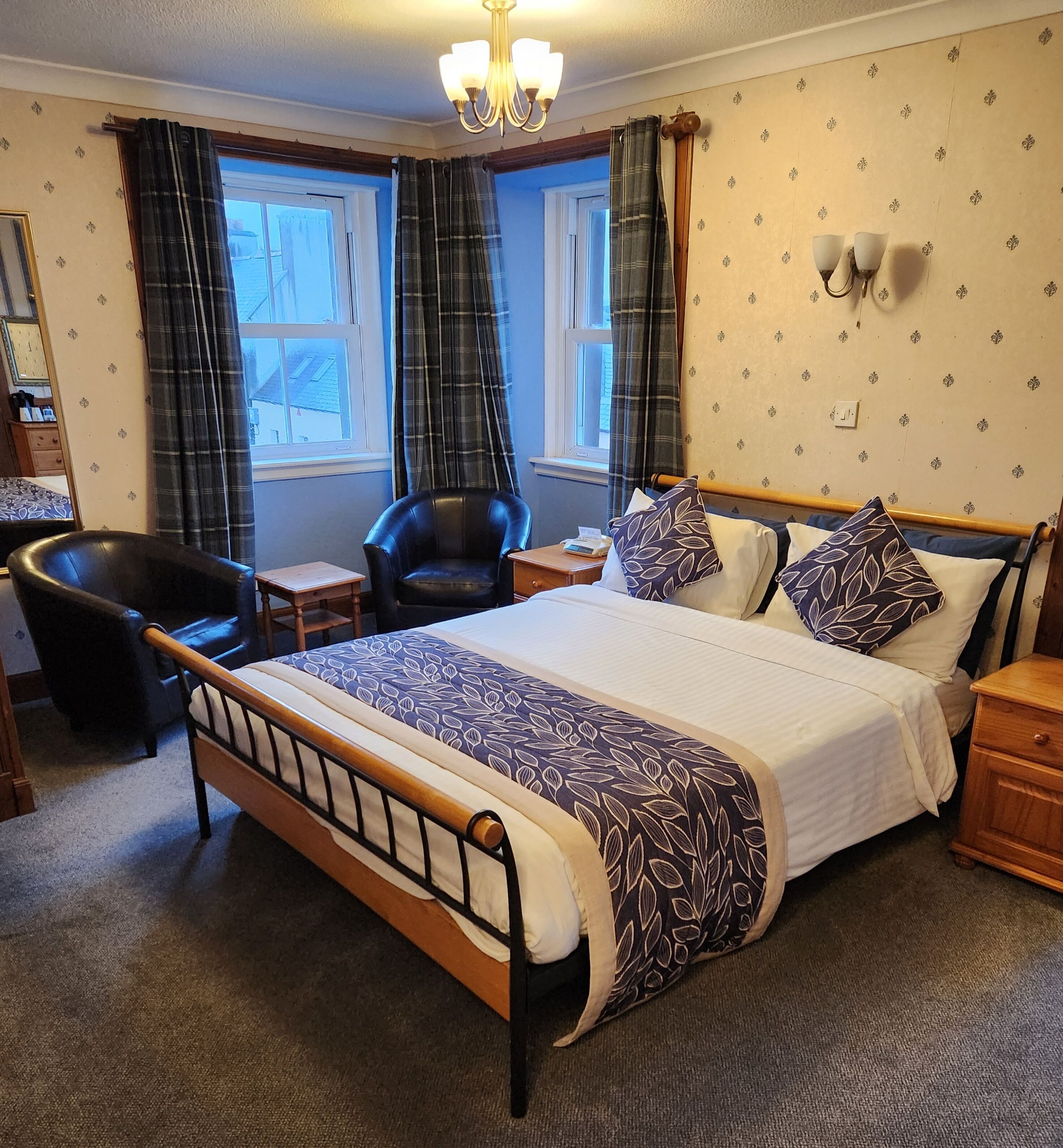 A neatly arranged bedroom with a large bed, a chair, a small table, and a desk.