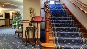 A grand staircase with blue carpeted steps and a wooden handrail, leading to an upper floor. - The Orkney Hotel (Kirkwall)