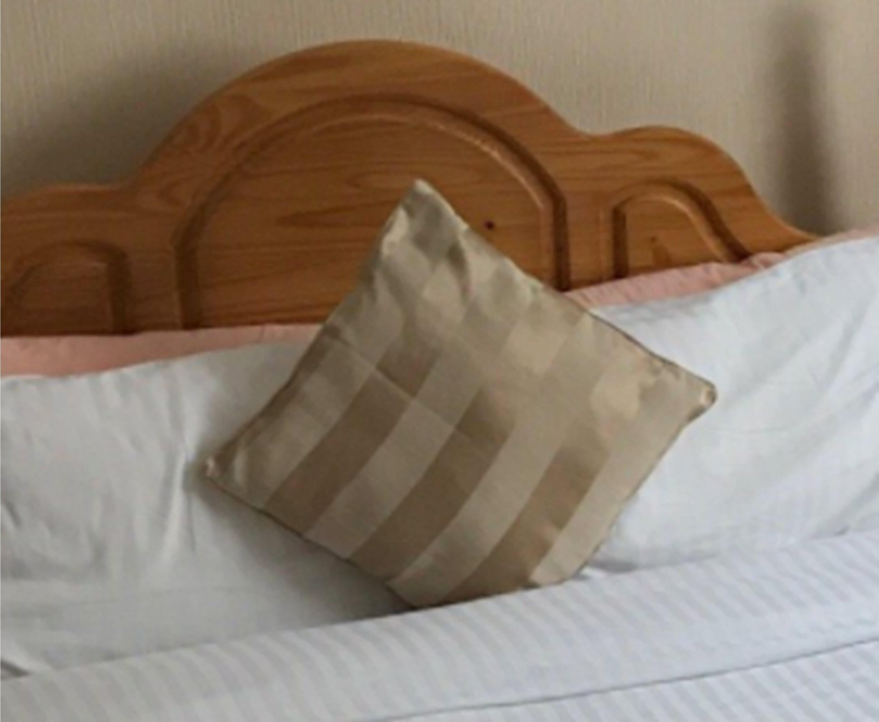 Una cama con cabecera de madera y almohada a rayas.