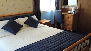 Una habitación de hotel con cama, escritorio, silla, cómoda y espejo.