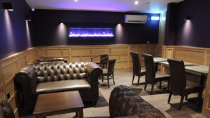 A restaurant with leather seating, wooden paneling, and a flat-screen TV mounted above a blue-lit fireplace. - The Orkney Hotel (Kirkwall)