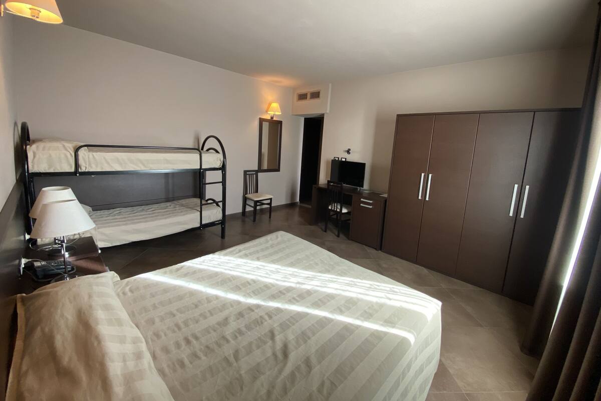 Ein Schlafzimmer mit zwei Etagenbetten, einem Schreibtisch mit Stuhl, einem Kleiderschrank und einer Lampe.