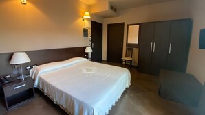 Ein Hotelzimmer mit Doppelbett, Nachttischen mit Lampen, einem Schrank und einem Sessel.