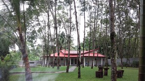 Uma casa com telhado vermelho cercada por árvores altas e um gramado bem cuidado.