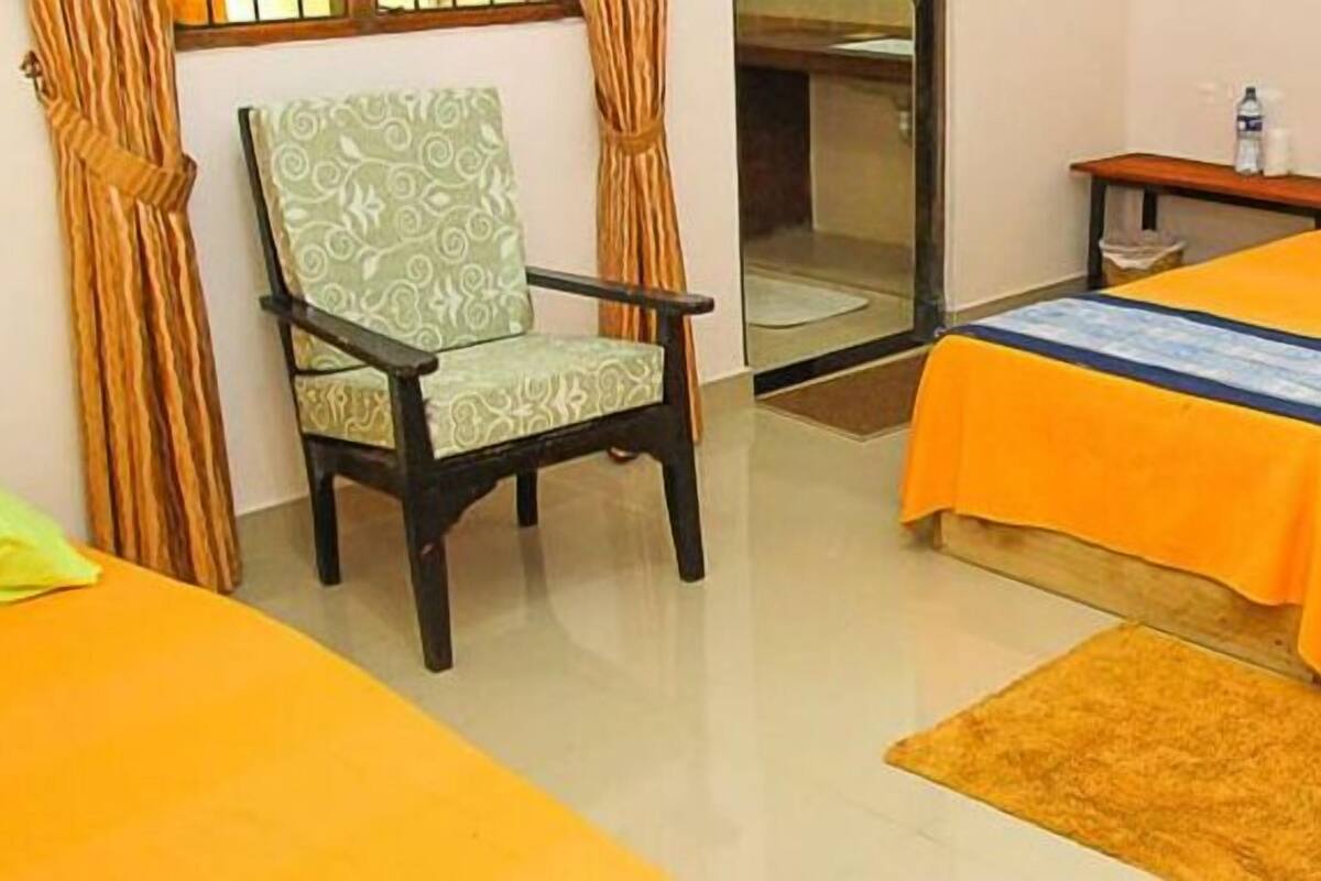 A hotel room with two beds, a chair, and a small table.
