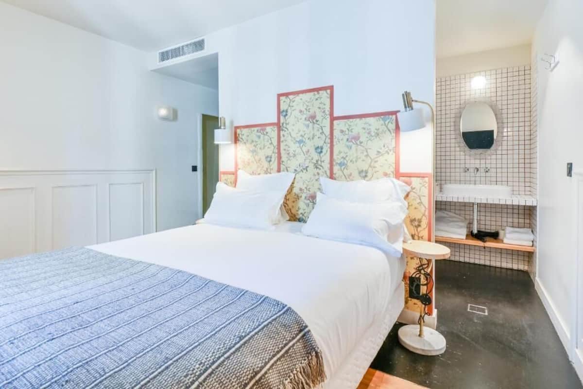 A hotel room with a bed, bedside table, and a small bathroom area.