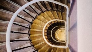 A spiral staircase with wooden steps and a central golden spiral. - Hôtel Habituel (Paris)