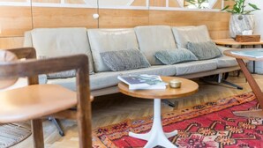 A modern interior with a sofa, a round table, and a patterned rug. - Hôtel Habituel (Paris)