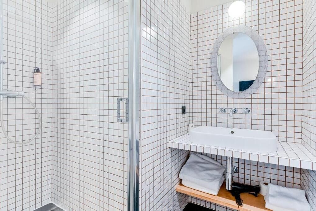 A bathroom with a shower, a sink, a mirror, and a towel rack.