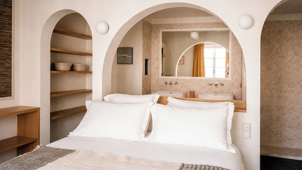 A bedroom with a bed, a vanity with a mirror, and a shelf with baskets. - Hôtel Habituel (Paris)