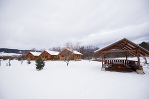 A wooden cabin complex with a covered picnic area in a snowy landscape. - Drevenice TriMount (Bobrovec)