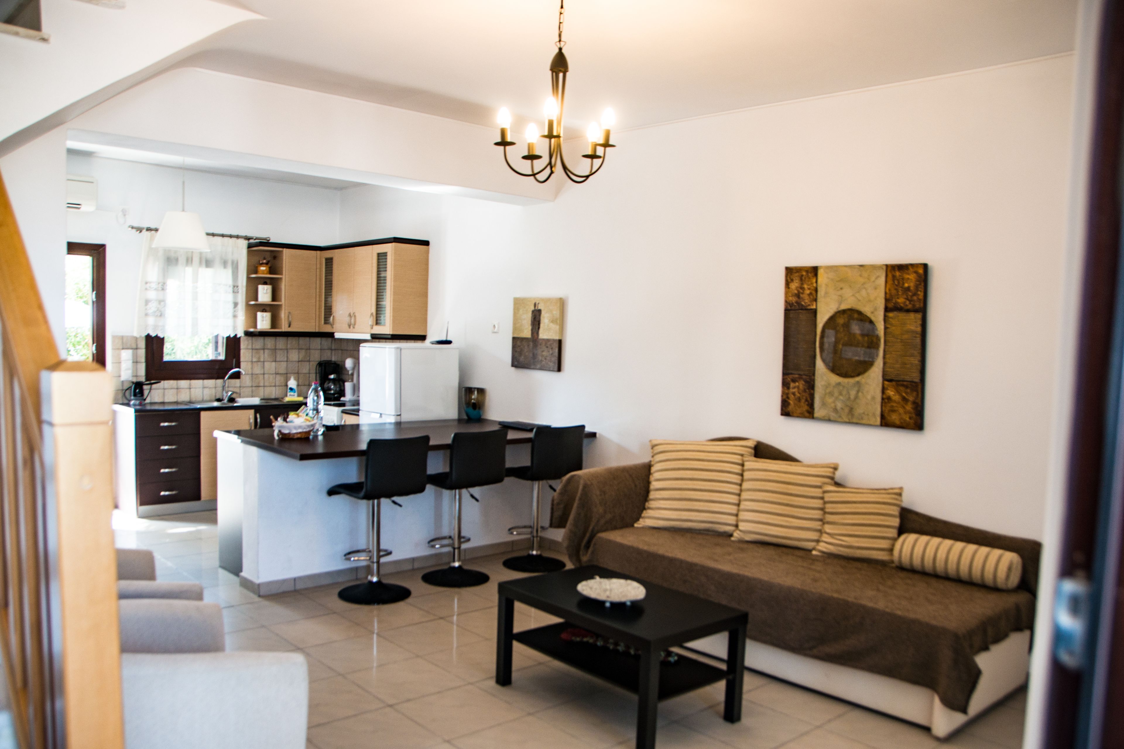 Un salon moderne avec un canapé, une table basse et un coin repas comprenant des chaises, et une cuisine en arrière-plan.