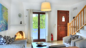 Uma sala de estar com lareira, sofá, mesa de jantar e escada.
