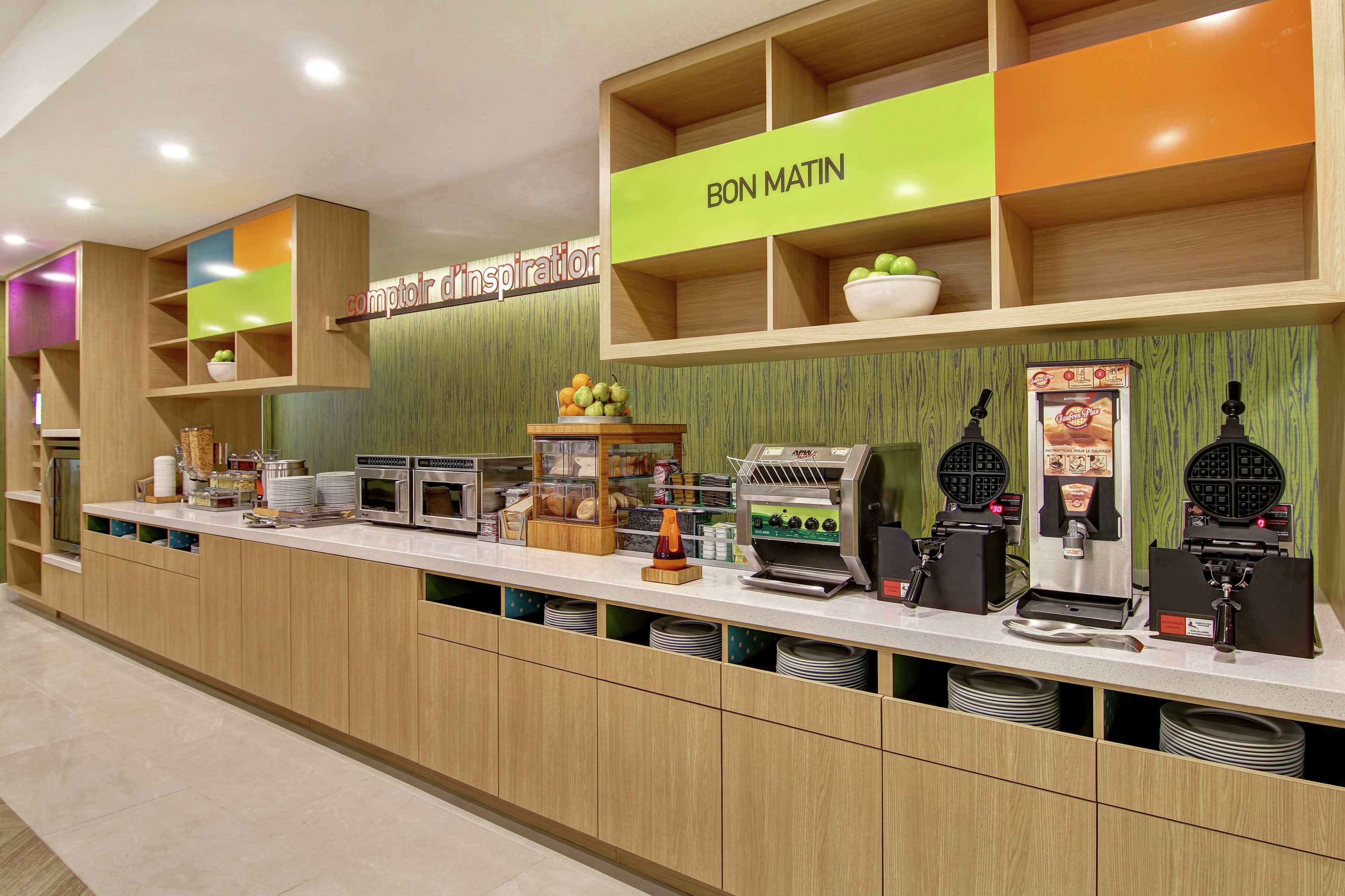 A breakfast bar with a variety of food items and a waffle maker.