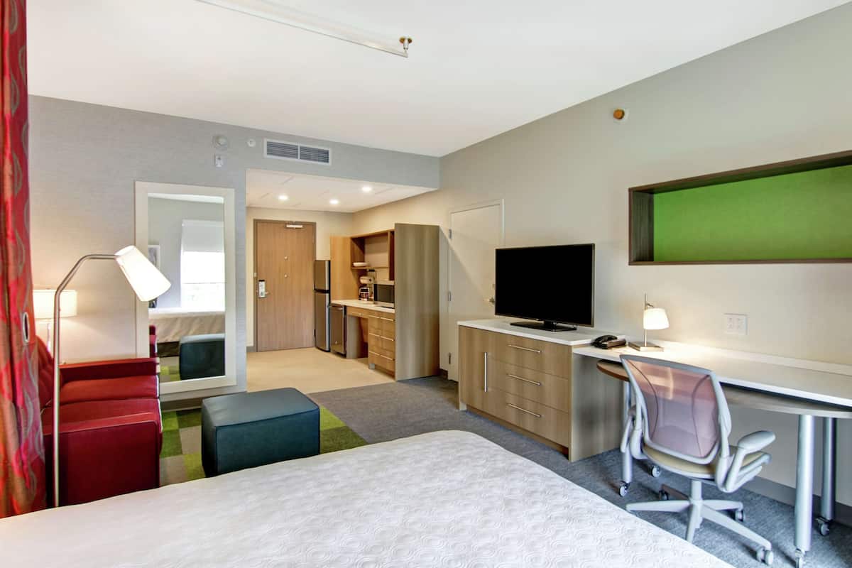 Een hotelkamer met een bed, bureau, televisie en kitchenette.