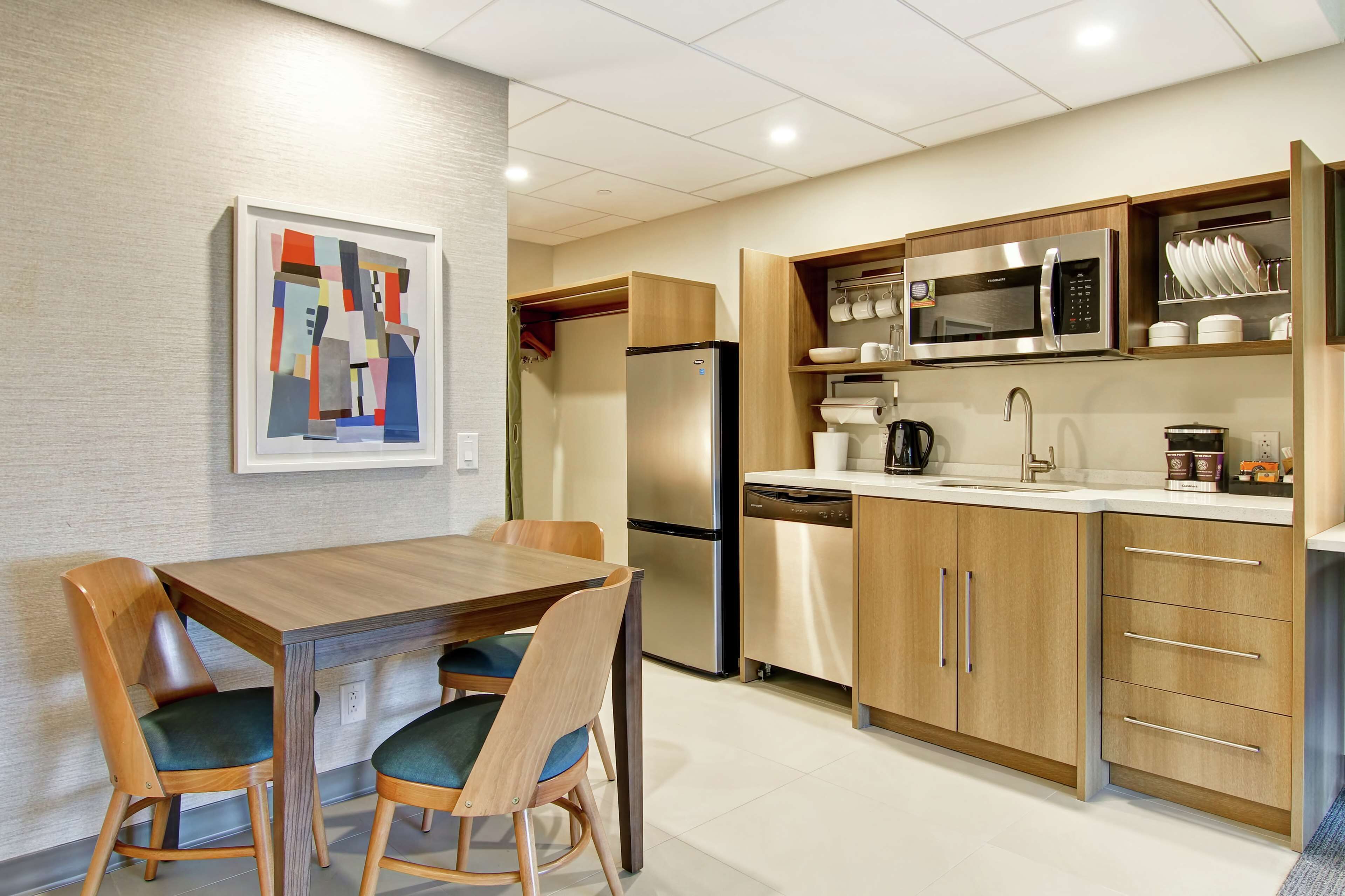A modern kitchen with a built-in microwave, stainless steel refrigerator, and wooden cabinets.