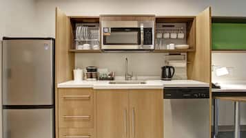 Una cocina compacta con refrigerador de acero inoxidable, microondas, lavavajillas y armarios de madera.