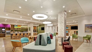 Een moderne hotel lobby met een centraal zitgedeelte, een keuken en een bar.