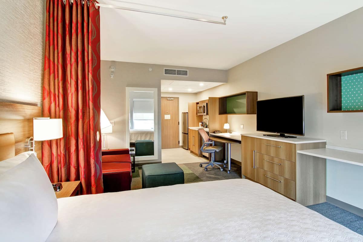 Een hotelkamer met een bed, bureau, televisie en kitchenette.