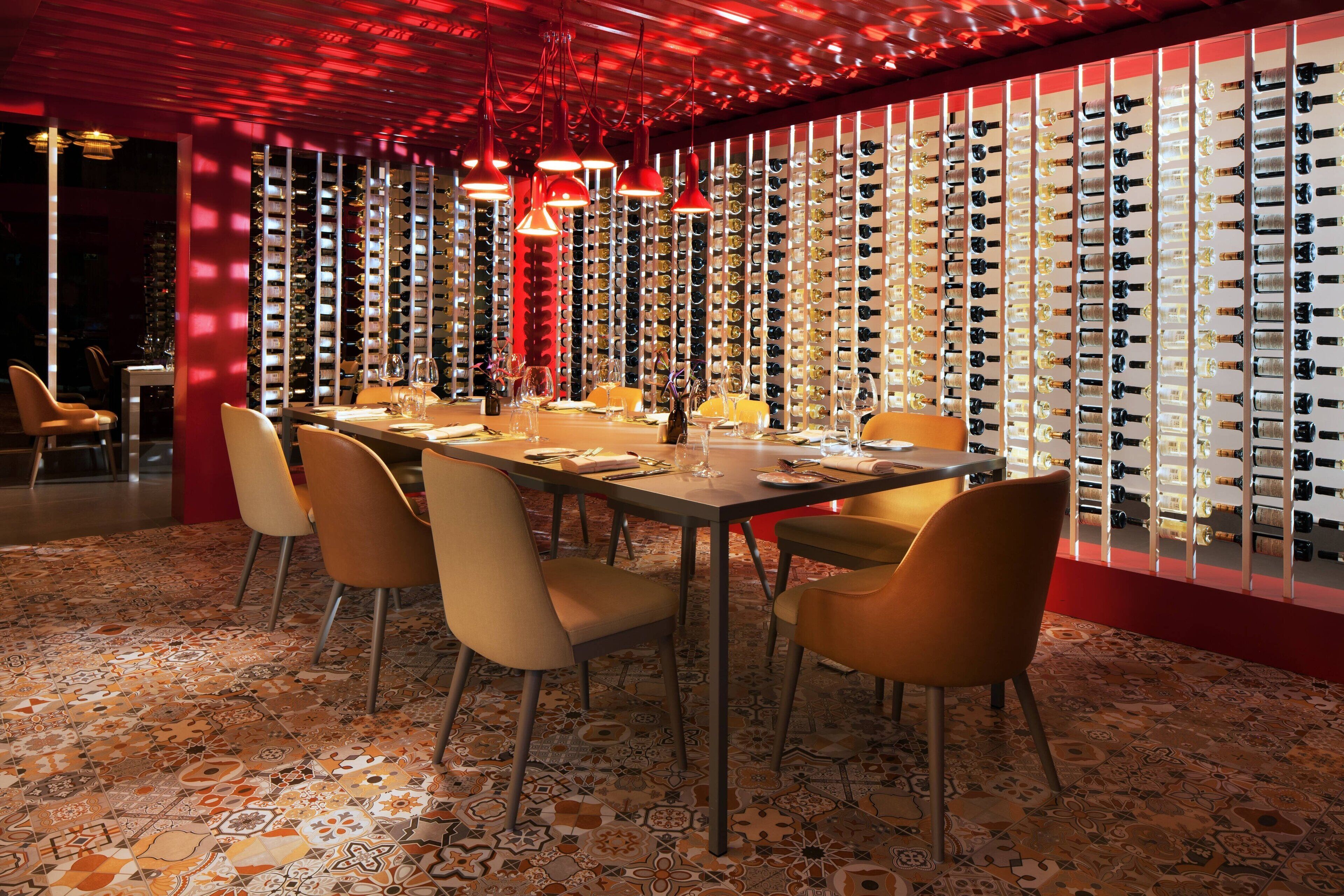 A dining area with a long table, multiple chairs, and a wine rack in the background.