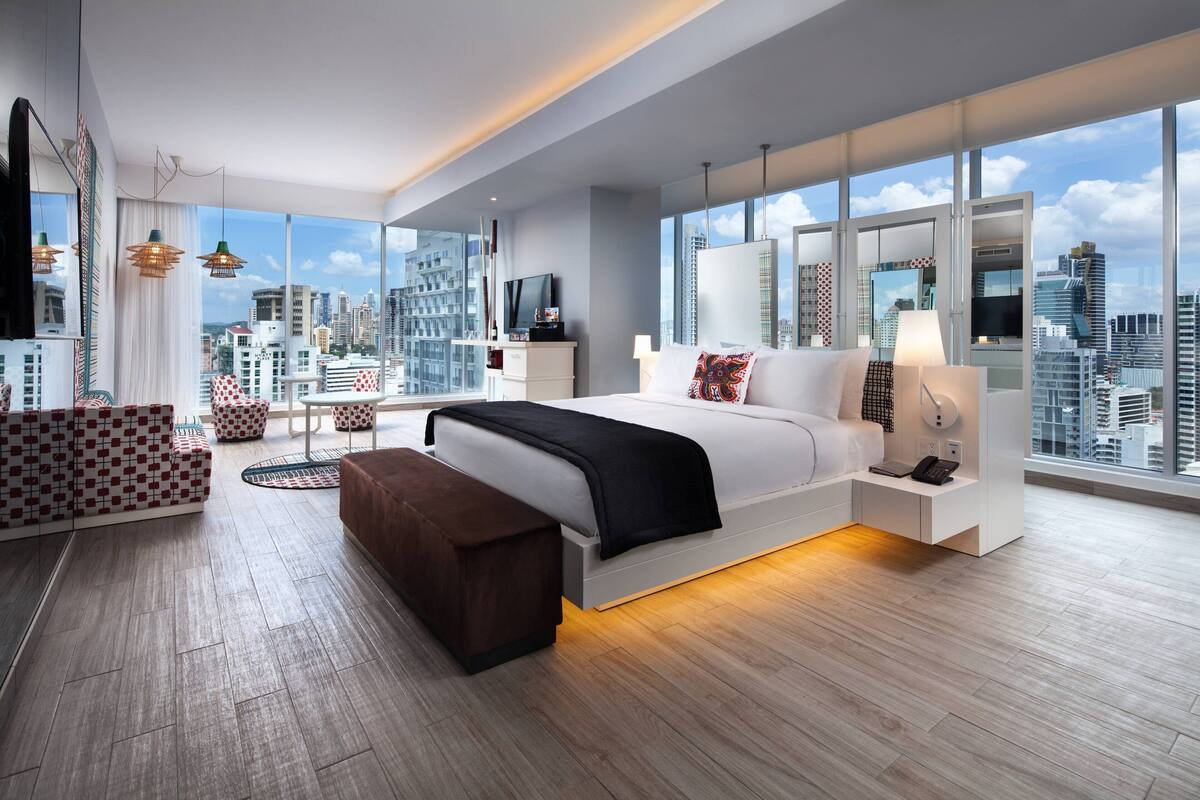 Habitació d'hotel moderna amb un llit gran, una taula de treball, una cadira i vistes a la ciutat.