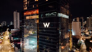 A modern high-rise building with a prominent 'W' logo, surrounded by other buildings and a busy street at night. - W Panama (Panama City)