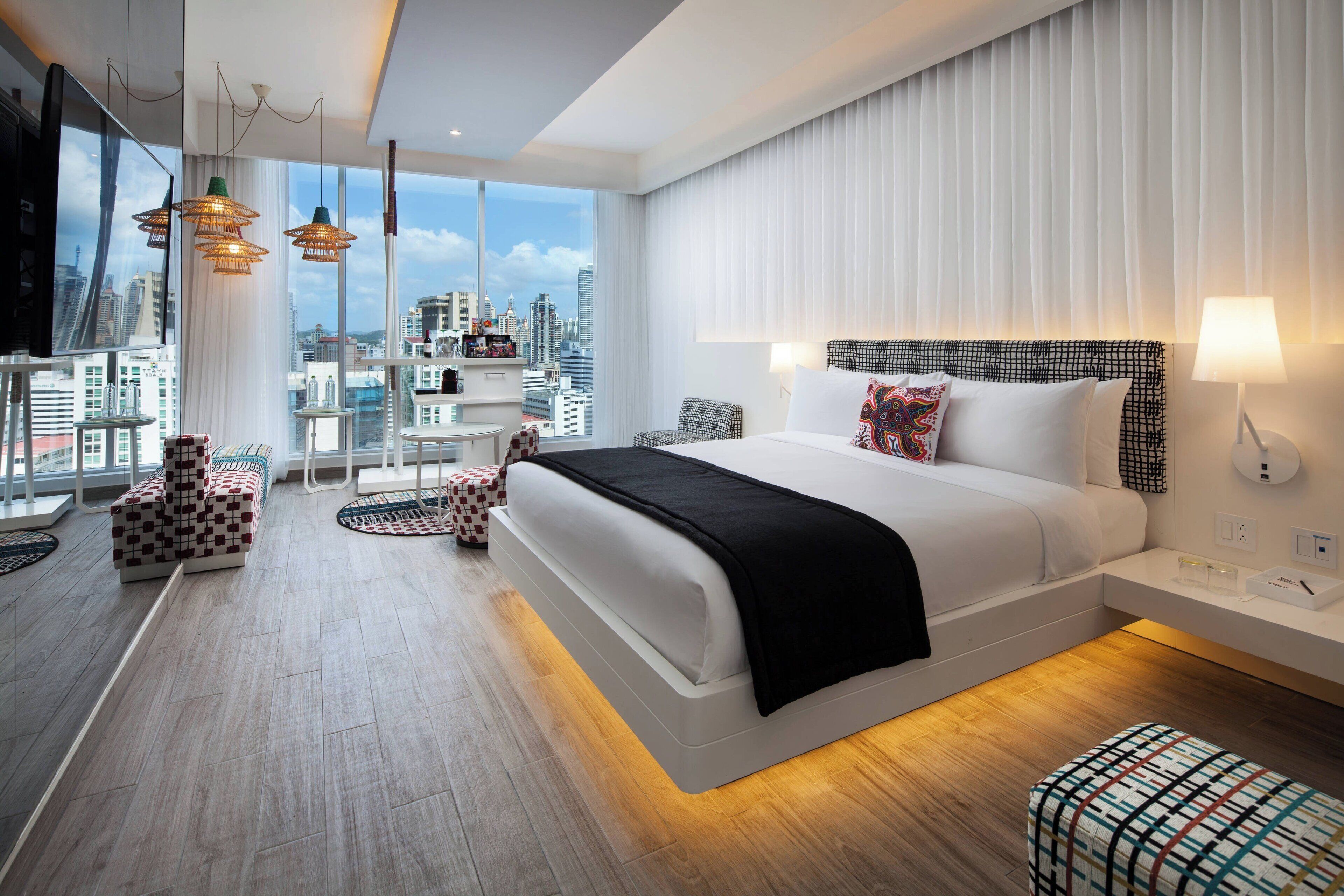 Ein modernes Hotelzimmer mit großem Bett, Blick auf die Stadt, einem Balkon und zeitgemäßer Einrichtung.