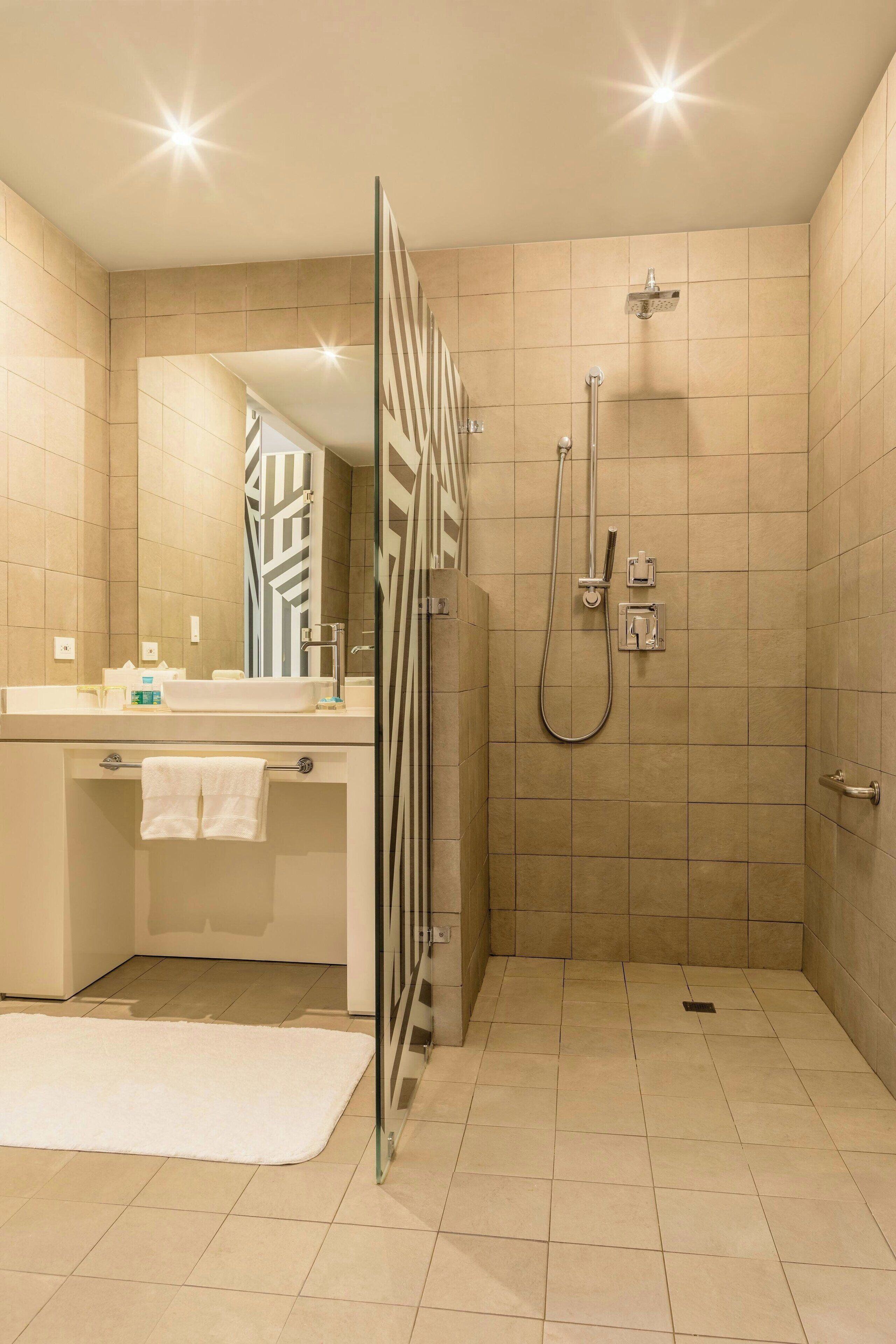 Ein modernes Badezimmer mit Dusche, Waschbecken mit Spiegel und Handtuchhalter.