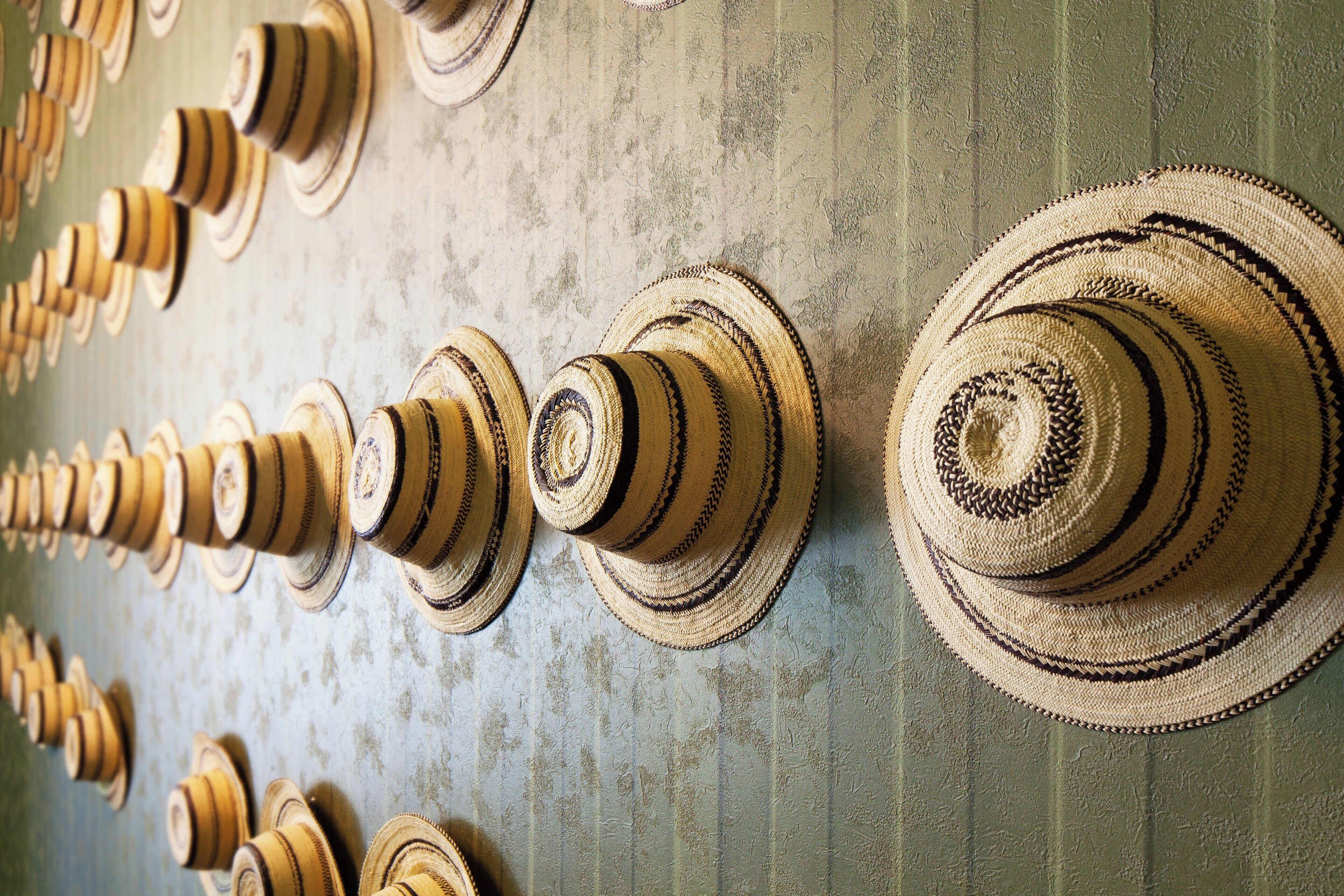 Un mur où est exposée une collection de chapeaux tissés.