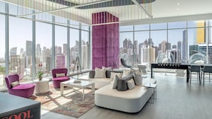 A modern living room with a city view, featuring a purple accent wall, a white sofa, and a glass table. - W Panama (Panama City)