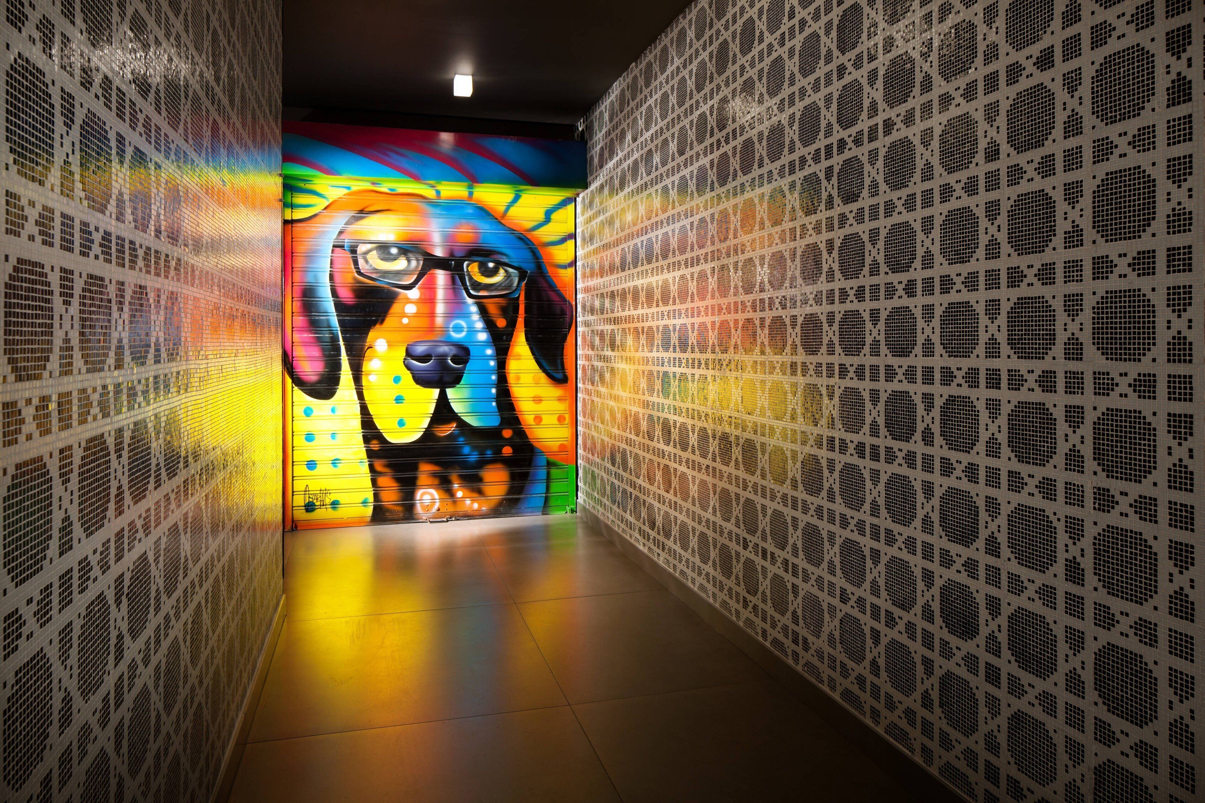 A corridor with a colorful mural on the left wall and a patterned wall on the right.