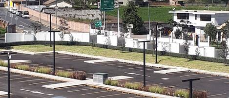 Un estacionamiento con varios coches, un cartel verde y una vista de una montaña al fondo.