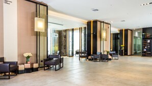 Un vestíbulo amplio con asientos modernos, una mesa de recepción y un muro de cristal que ofrece vistas del interior.