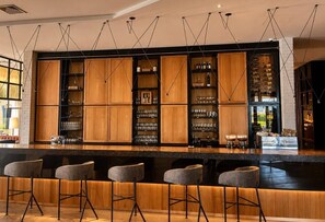 A bar area with wooden cabinets, bar stools, and hanging light fixtures. - Eb hotel By Eurobuilding Quito Airport (Tababela)