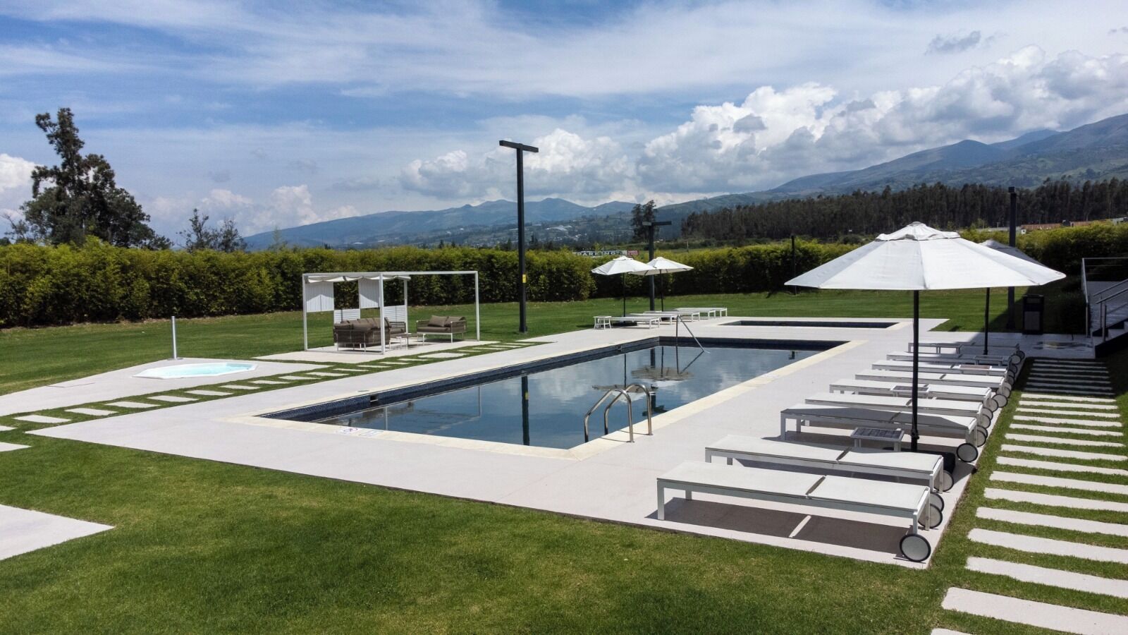 A rectangular swimming pool with a diving board, lounge chairs, and umbrellas.
