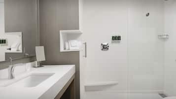 Un baño moderno con un lavamanos grande, espejo y ducha.