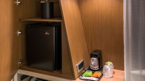 Ein kompaktes Hotelzimmer mit integrierter Küchenzeile, inklusive Kühlschrank, Kaffeemaschine und einem kleinen Heizgerät.