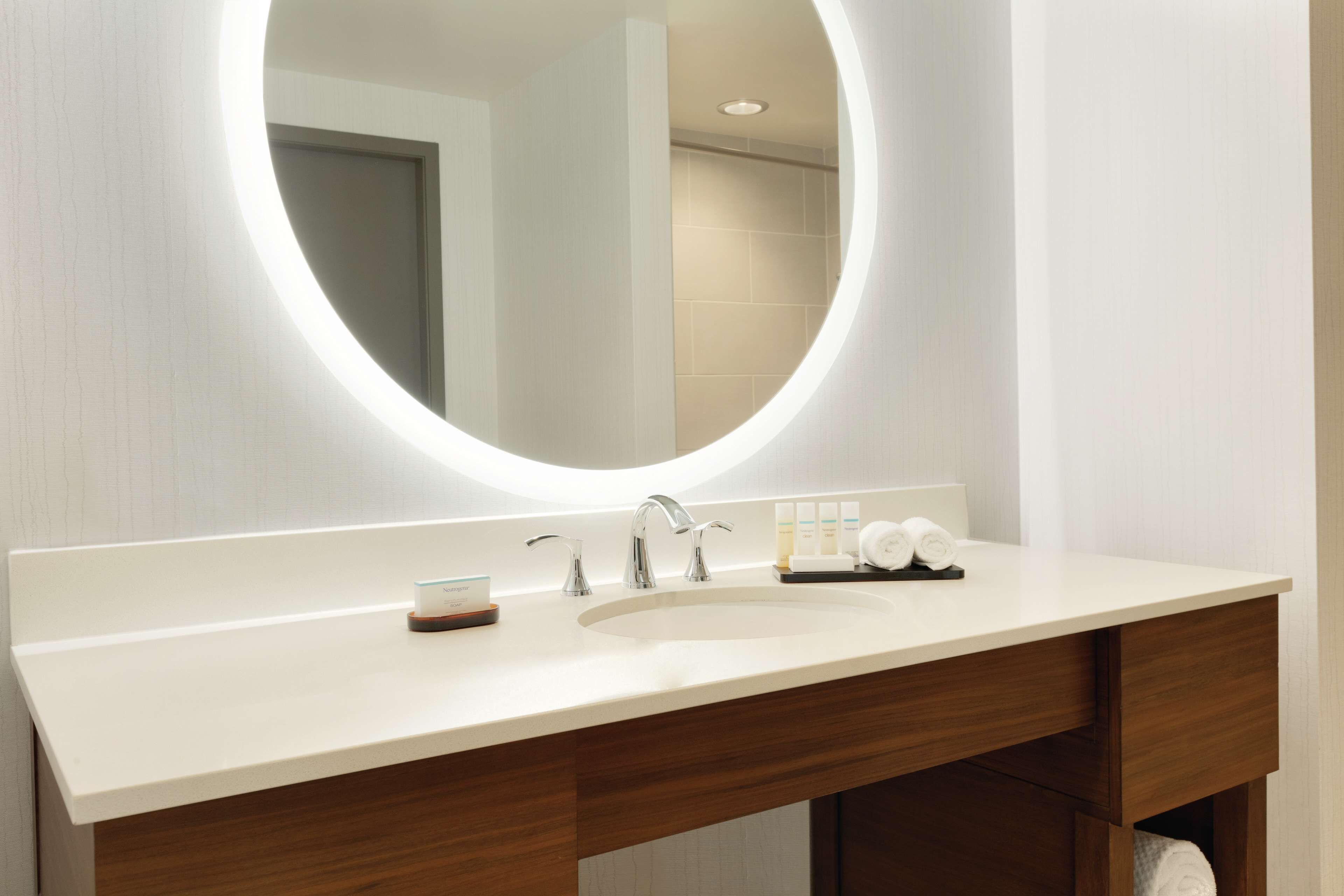 A modern bathroom with a white vanity, a round mirror, and a sink.