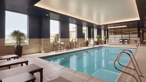A modern indoor pool area with seating and a view of the city. - Embassy Suites by Hilton South Jordan Salt Lake City (South Jordan)
