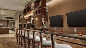 A bar area with wooden chairs, a counter, and two large flat-screen TVs mounted on the wall. - Embassy Suites by Hilton South Jordan Salt Lake City (South Jordan)